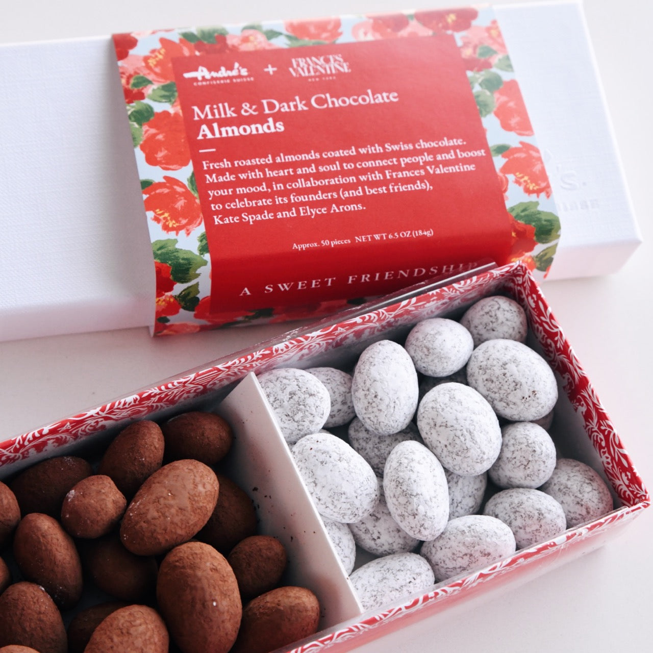 open box of milk and dark chocolate almonds with the white lid and signature Frances Valentine floral wrapper beside