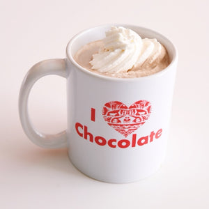 White mug with 'I ❤️ Chocolate' text, filled with hot chocolate and whipped cream.