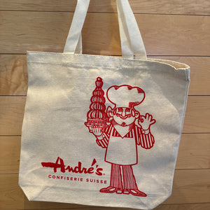 Tote bag with red logo and text on a wooden surface