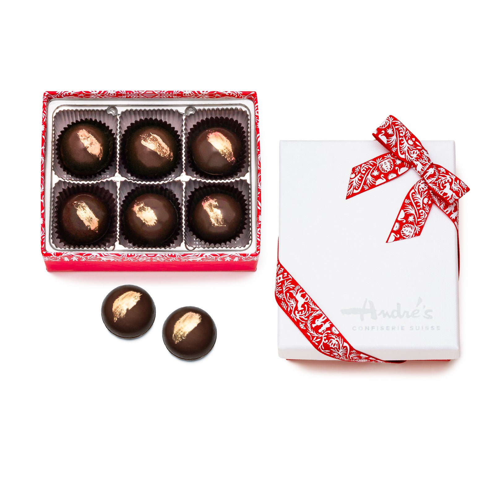 6 dark chocolate round truffles with gold brushstroke design on top in a red box, 2 loose chocolates, and the closed box with white "Andre's" logo lid and red Swiss print ribbon