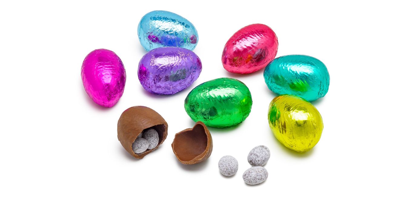 brightly colored foil covered chocolate eggs, with one uncovered and broken to reveal milk chocolate covered almonds inside 