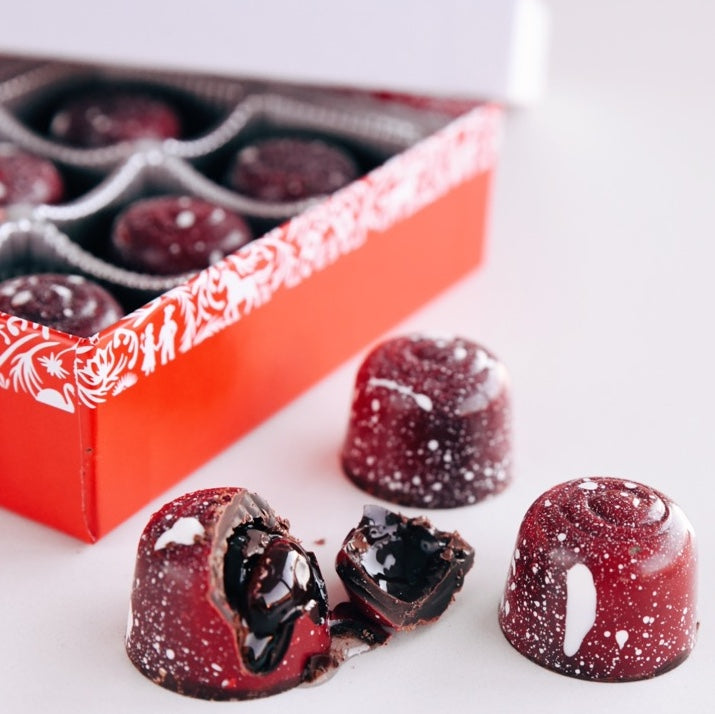 Box of chocolate bonbons with whole and broken candies in foreground.