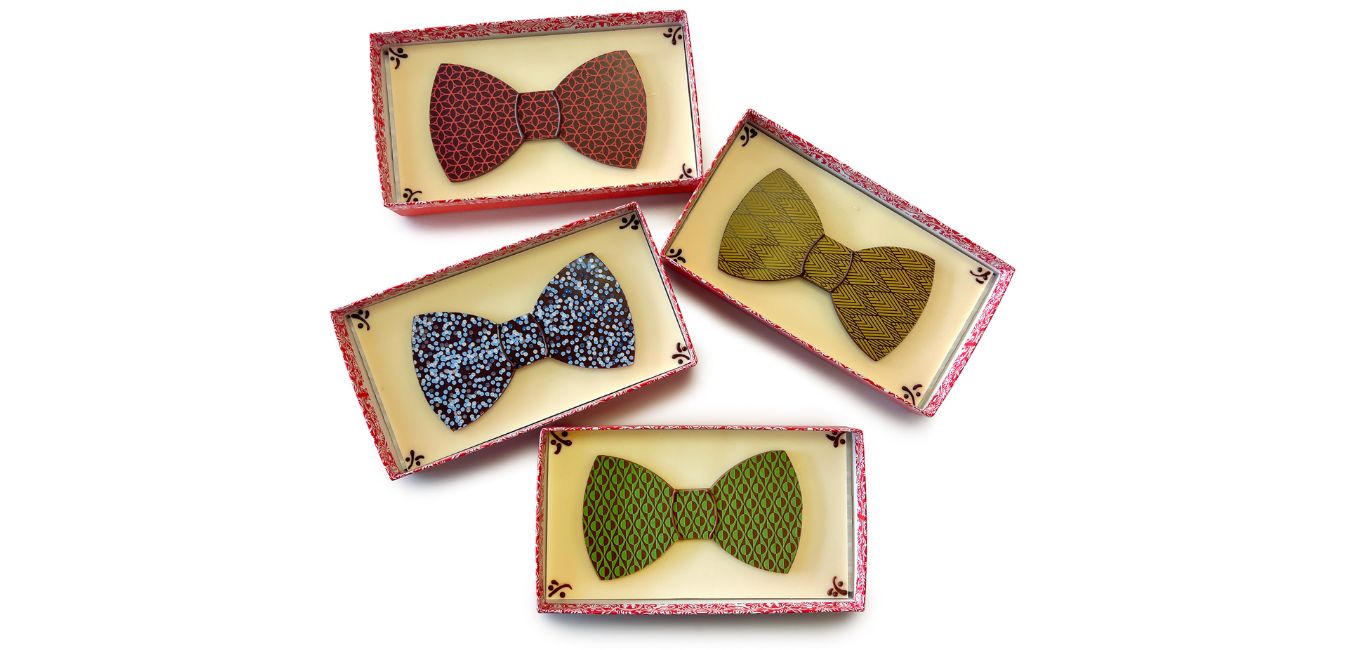 overhead view of 4 boxes - each with white chocolate bases and 2D brightly colored chocolate bow ties inside