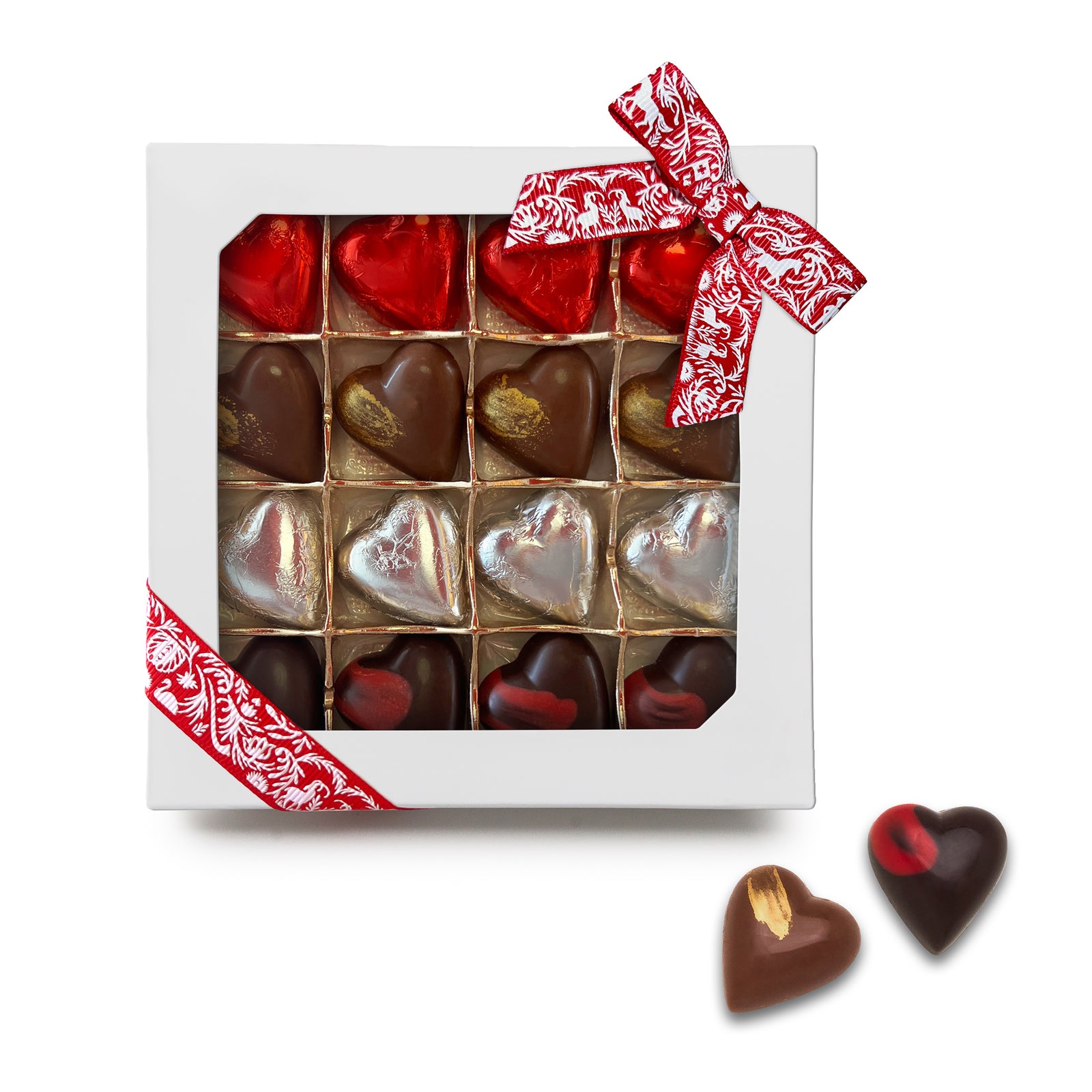 Red Swiss ribbon on white window box with 4 rows of 4 chocolate hearts visible inside: red foil covered, milk chocolate with gold brushstroke, silver foil covered, dark chocolate with red brushstroke. 2 loose hearts beside