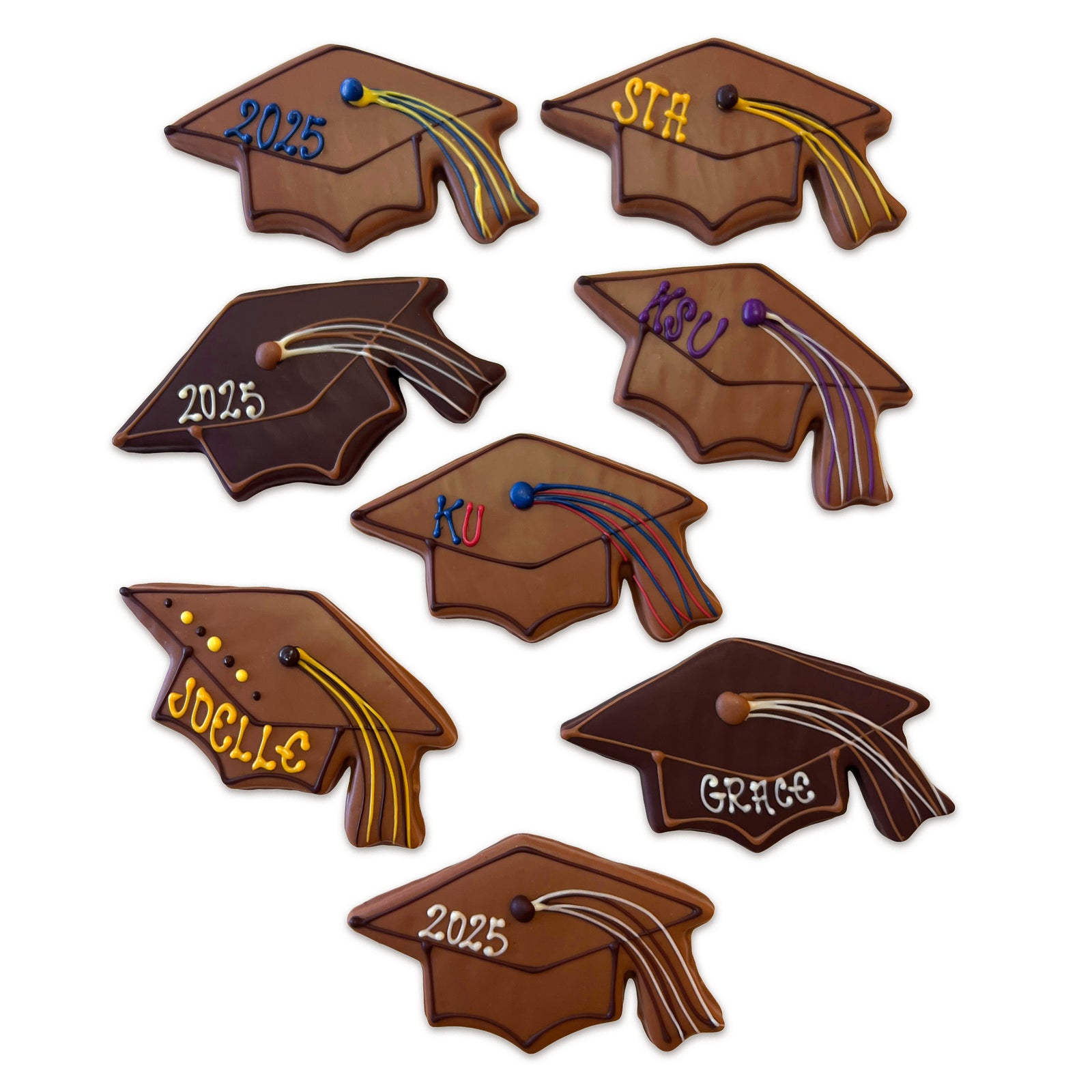 Several chocolate coated cookies shaped like graduation mortarboard caps, each with either a name, school initials, or 2025 written in chocolate.