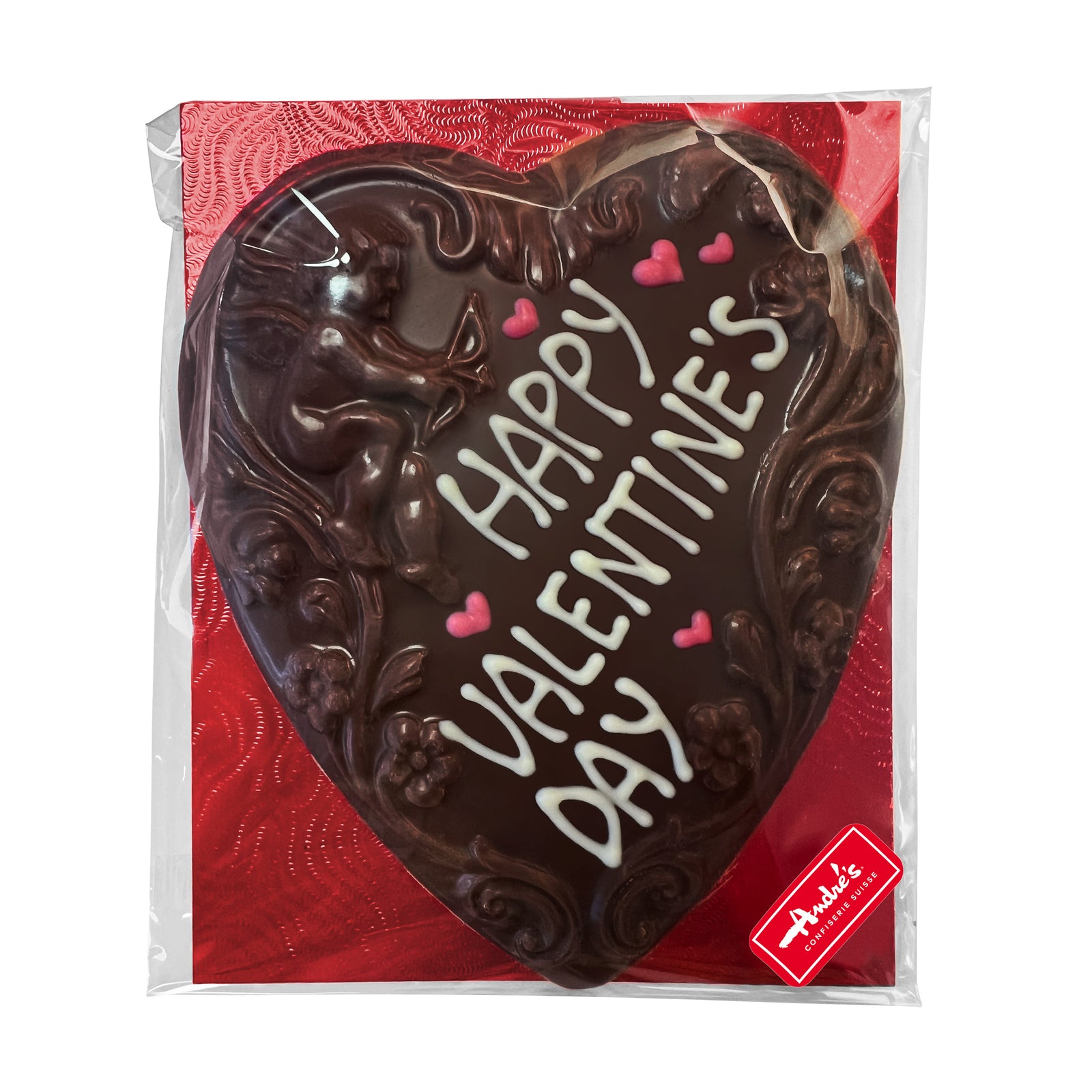 Dark chocolate heart with cupid and scoll design and "Happy Valentine's Day" written in white chocolate, sitting on a red base, in a clear bag.