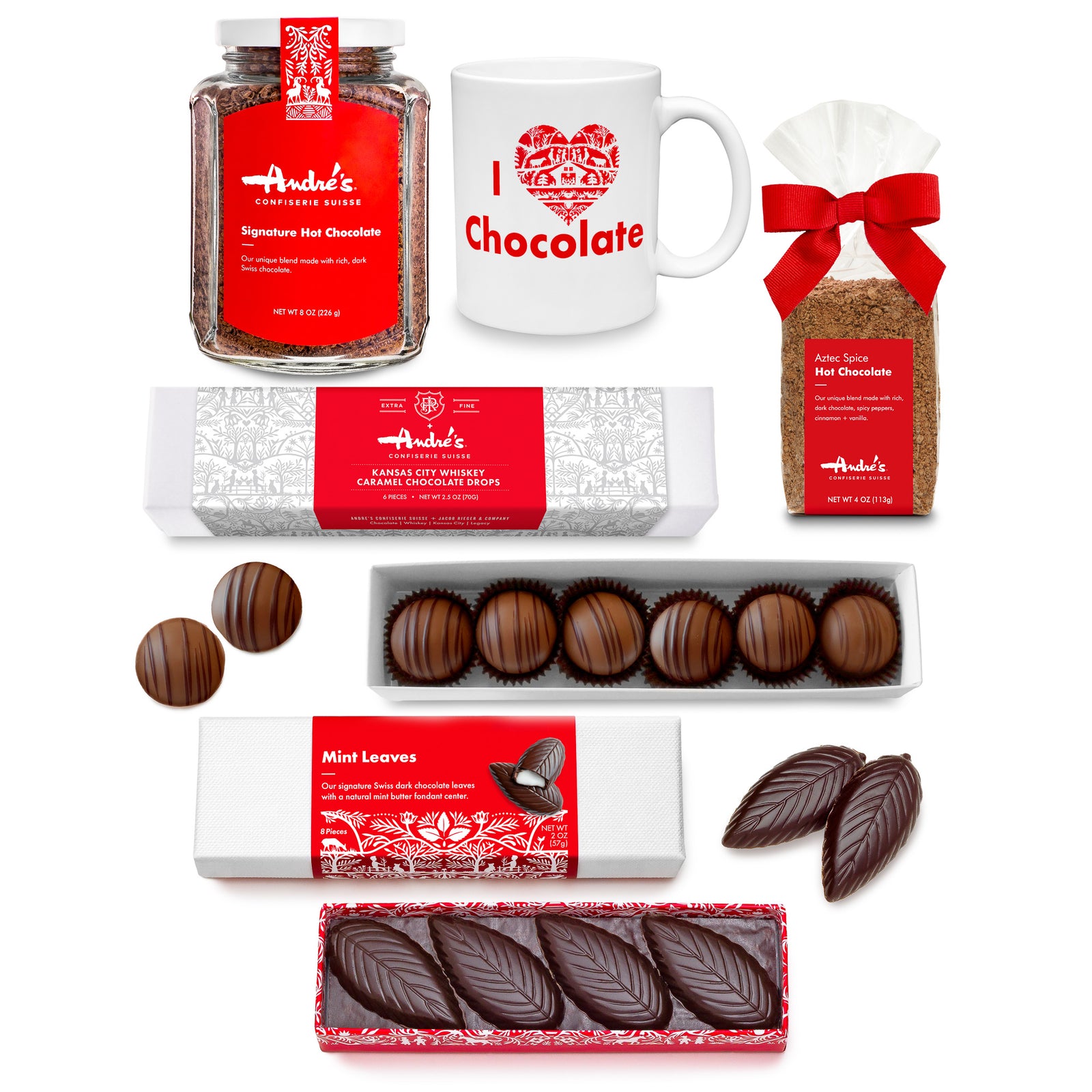 Collection of Ande's hot chocolate products including a Hot Chocolate jar, mug, hot chocolate bag, whiskey caramel drops box, mint leaves box. All with red & white Swiss print packaging on a white background.