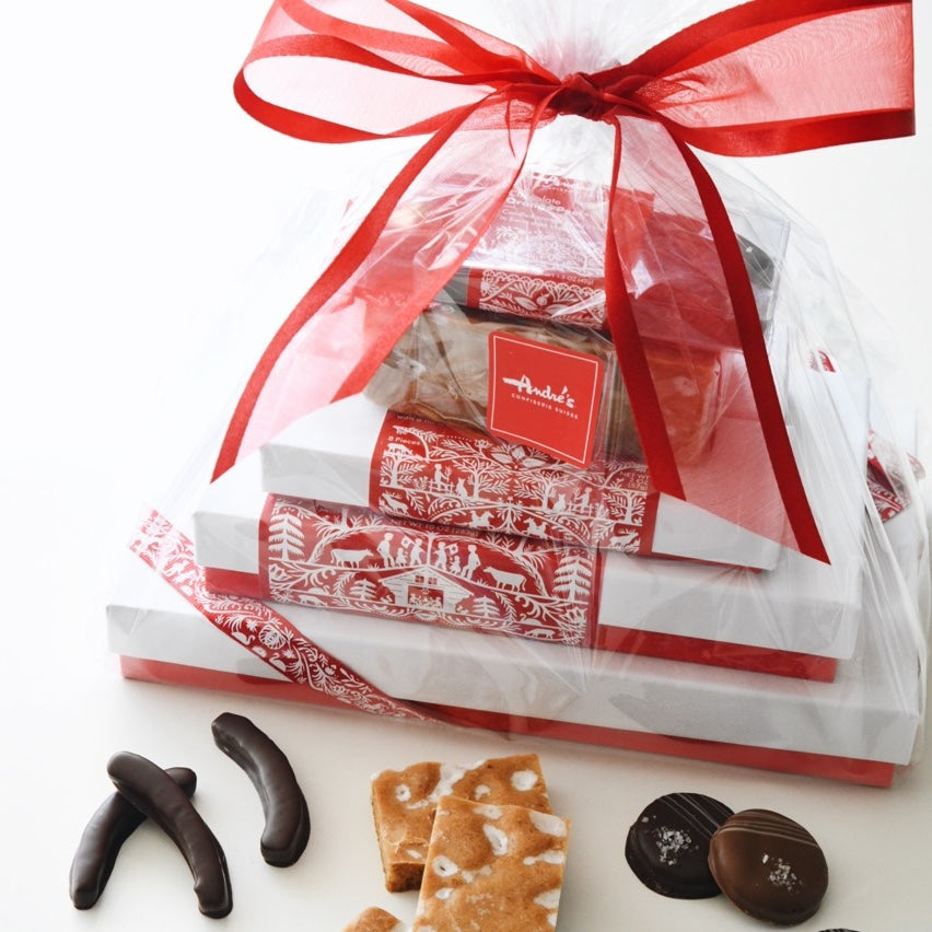 Clear cellophane bag tied with red ribbon containing a stack of red and white Andre's Swiss design boxes.  A few loose candies scattered on the table beside.