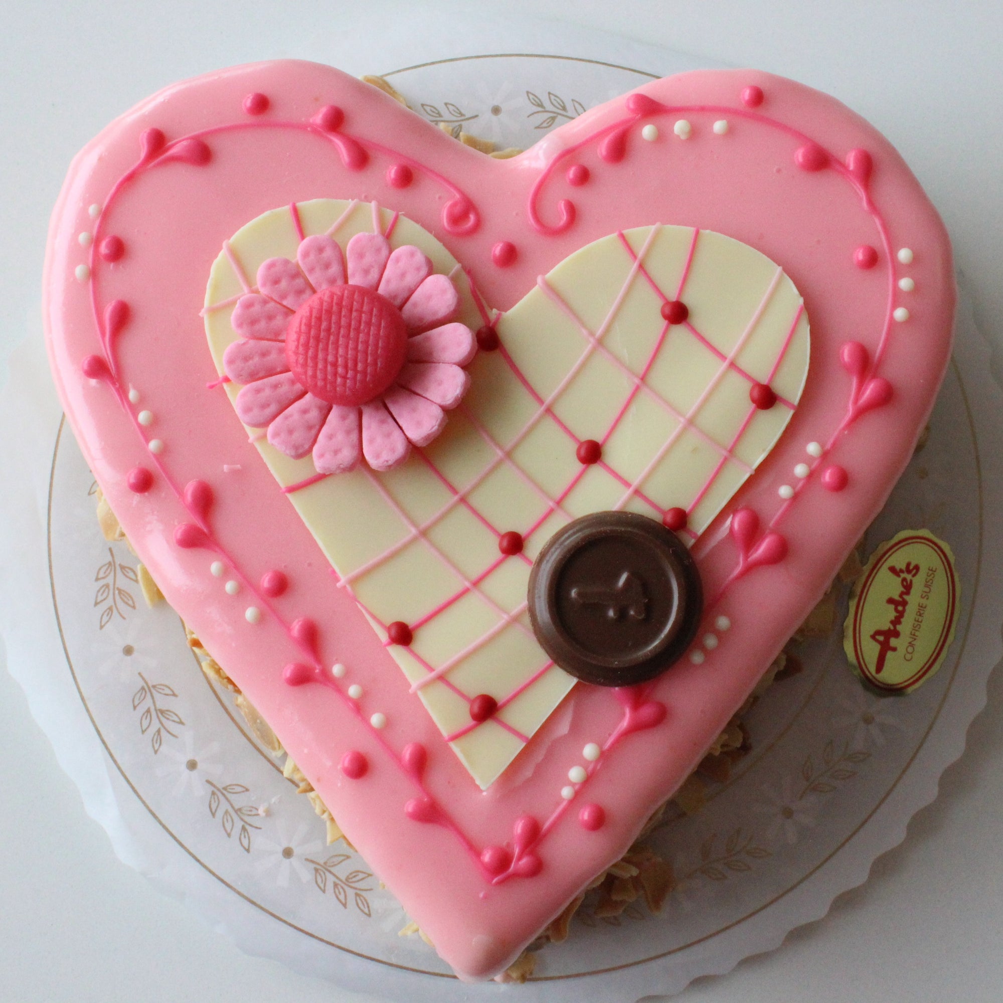 Heart shaped lemon torte with pink fondant and a white chocolate heart and pink flower decor.