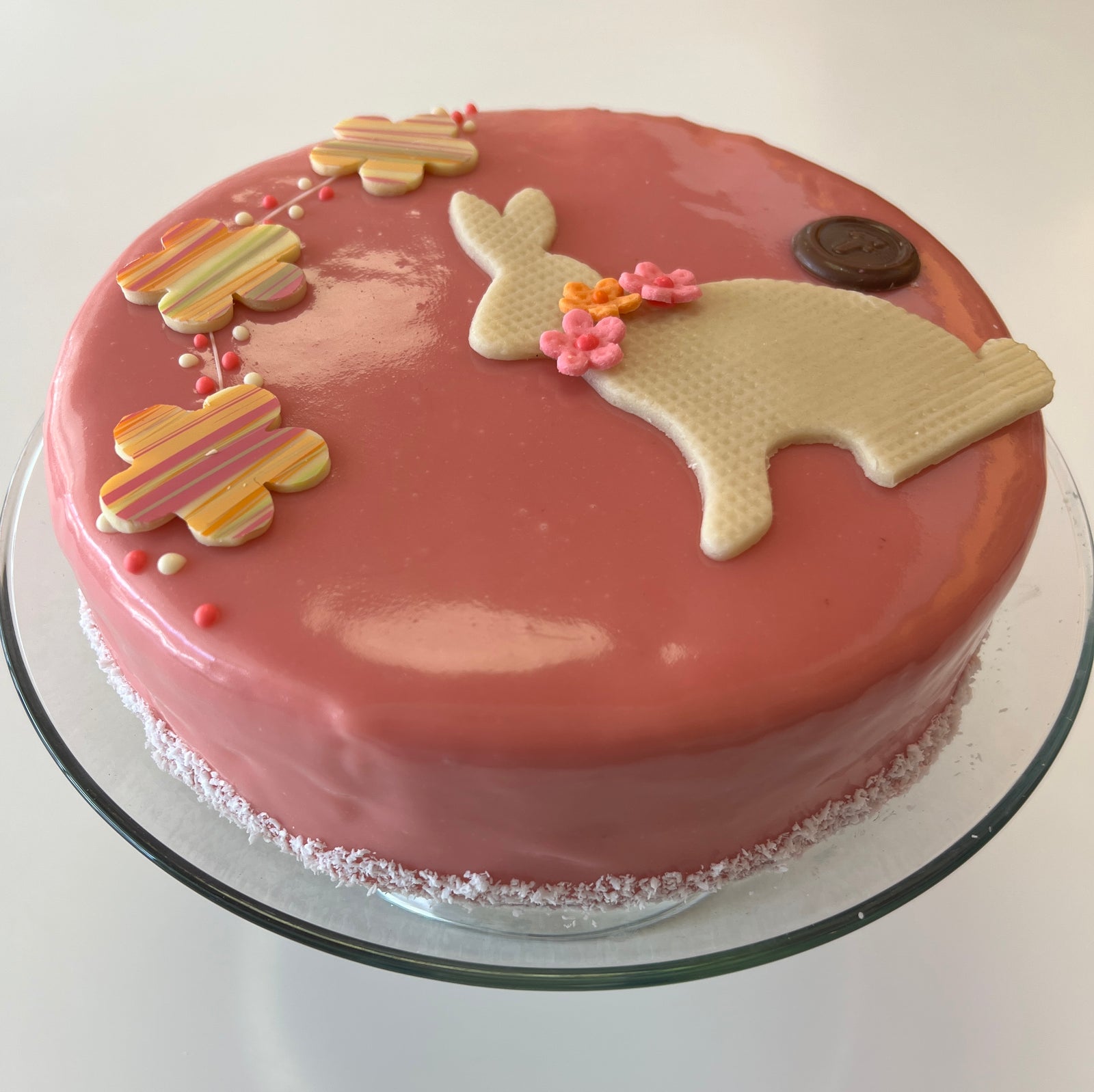 overhead view of pink round cake with white bunny and spring colored flowers 
