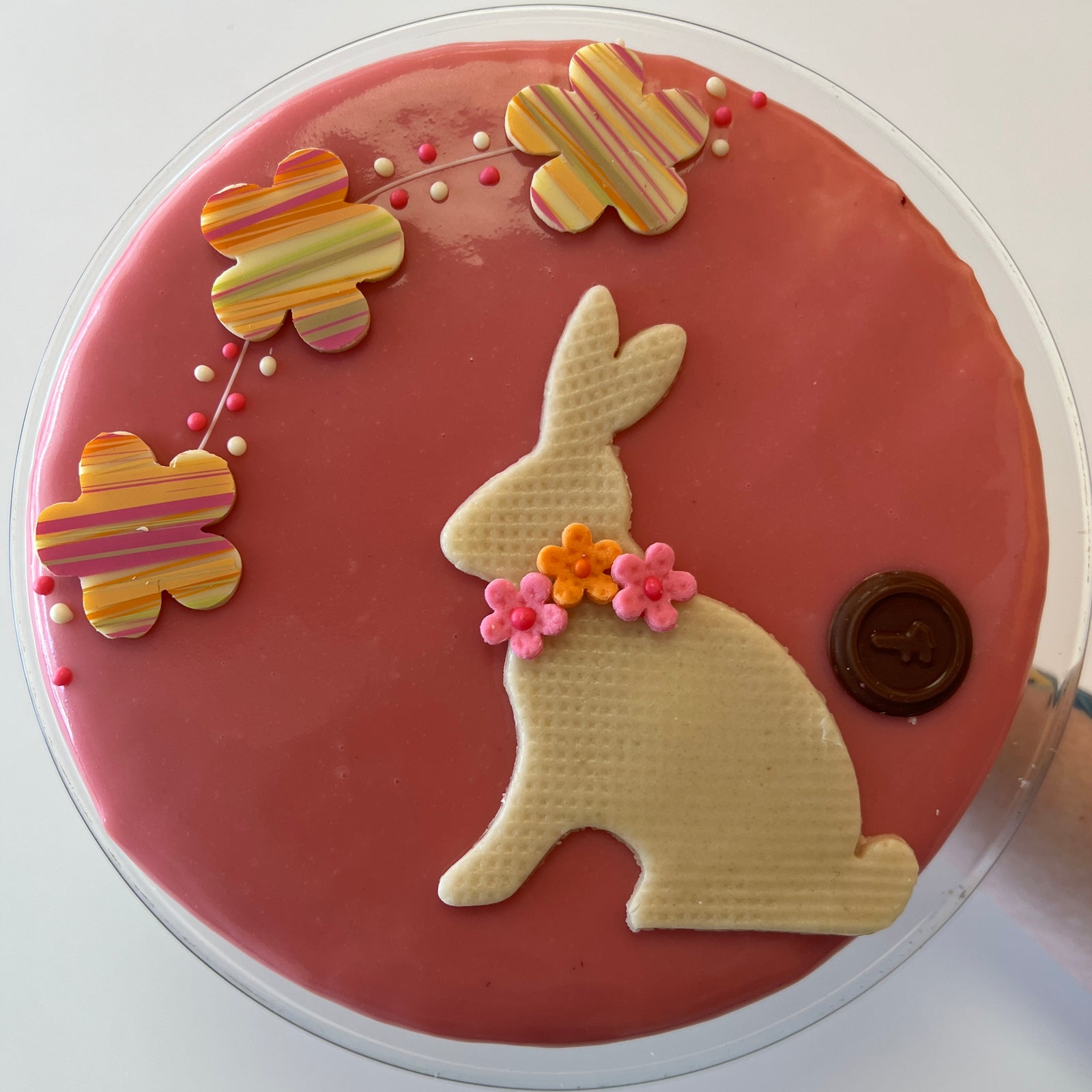 overhead view of pink round cake with white bunny and spring colored flowers 