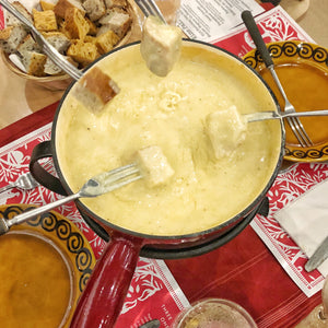 Cheese being enjoyed with bread and croutons on a festive tablecloth.