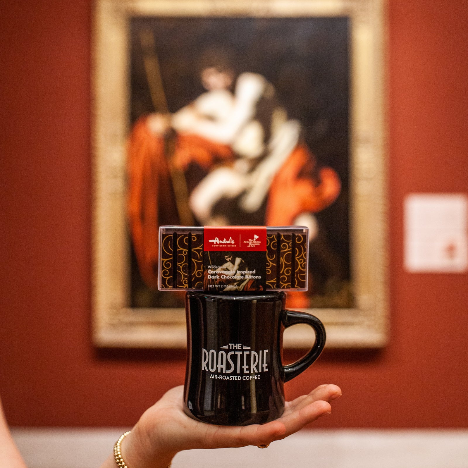 Dark chocolate sticks with reddish scroll designs and product label that features the artwork Saint John the Baptist in the Wilderness.  