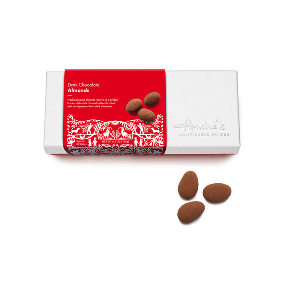 White logo box with red Swiss print product label next to a cluster of  cocoa powder covered chocolate almonds.