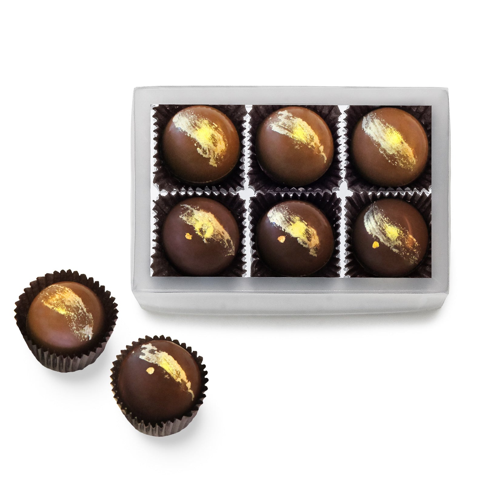 A clear box with 3 milk chocolate balls and 3 dark chocolate balls, each with a gold brush stroke. One of each candy is also beside the box.