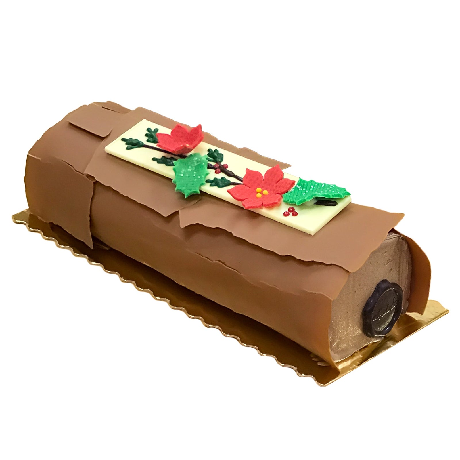 Log shaped cake covered in chocolate that looks like bark with marzipan decor to resemble poinsettia and holly.