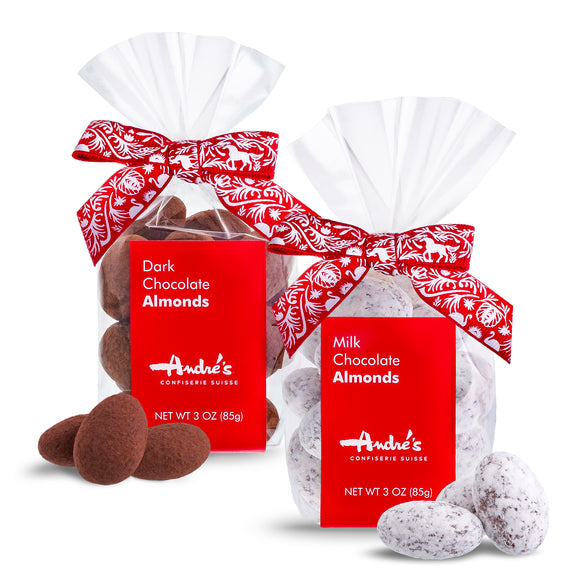 Dark chocolate almonds in a clear bag with red product label and Swiss print bow next to a bag with powdered sugar coated milk chocolate almonds inside.