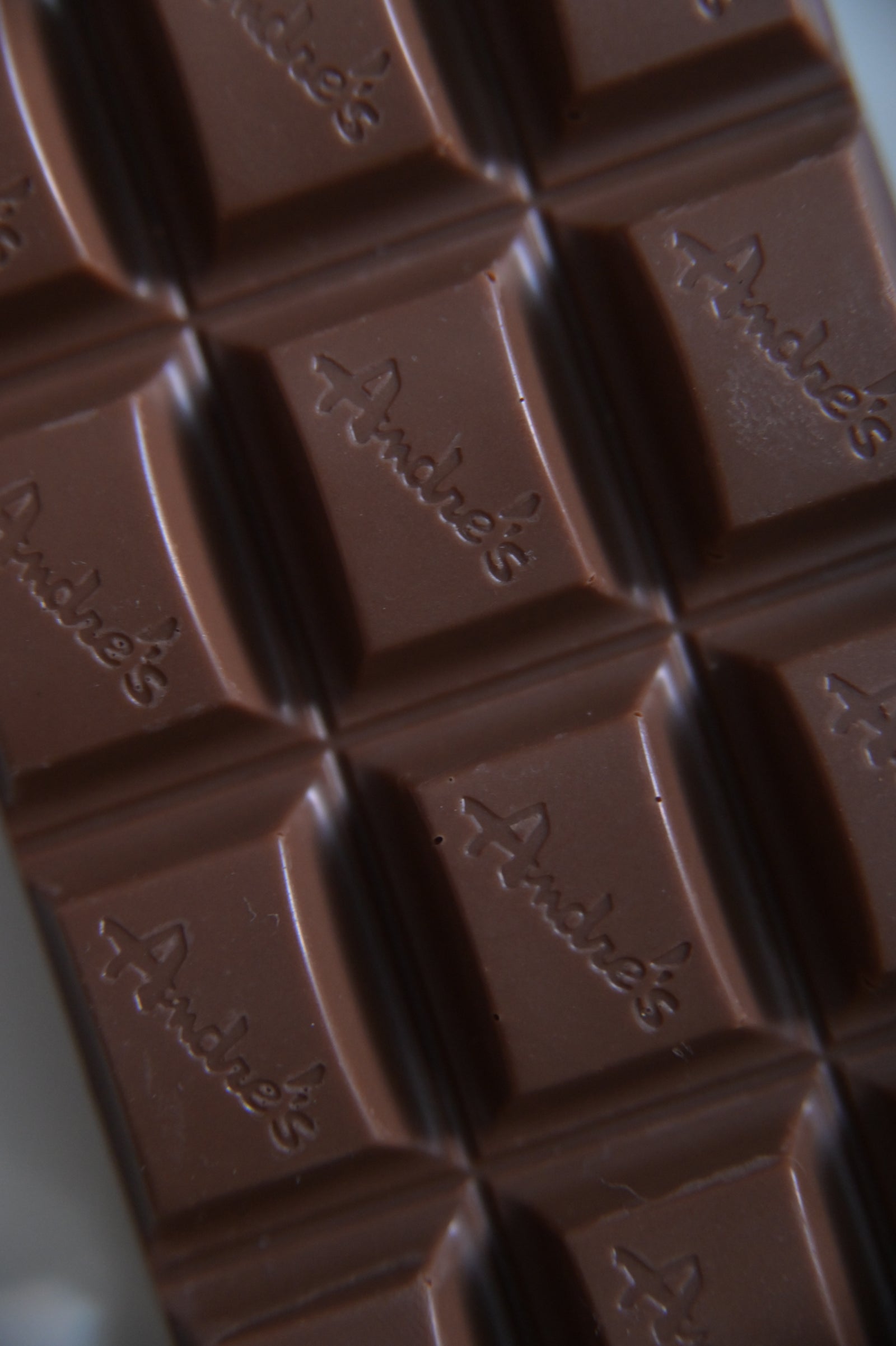 Three chocolate bars in a variety of flavors, from left to right: dark chocolate, white chocolate, and milk chocolate, all with red packaging.