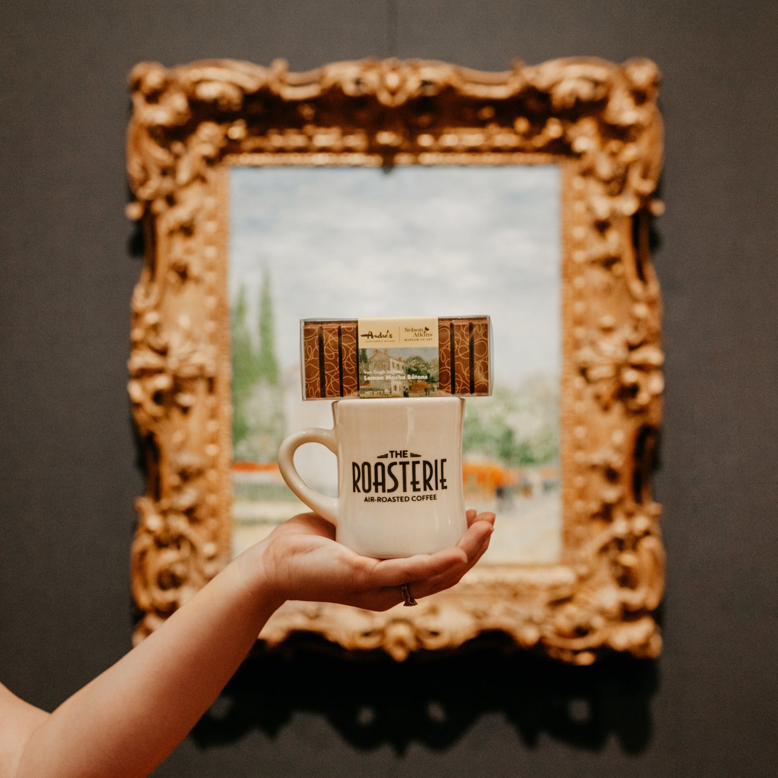 A clear box with dark chocolate sticks with yellow designs with a product label that showcases a Van Gogh painting.