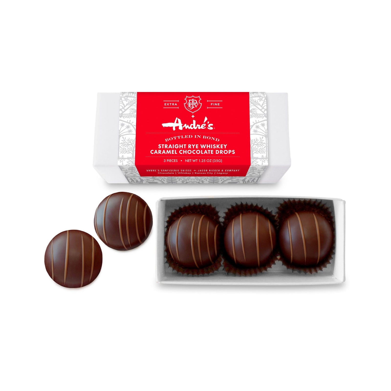 3 dark chocolate balls in a white box and 2 loose beside the box, below a sealed white box with red and silver patterned product label.