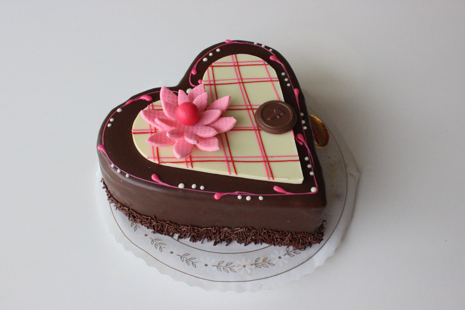Heart shaped lemon torte with pink fondant and a white chocolate heart and pink flower decor.