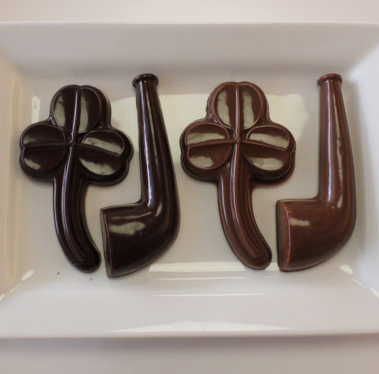 A chocolate shamrock and a chocolate pipe, each in a clear bag with green shamrock bows.