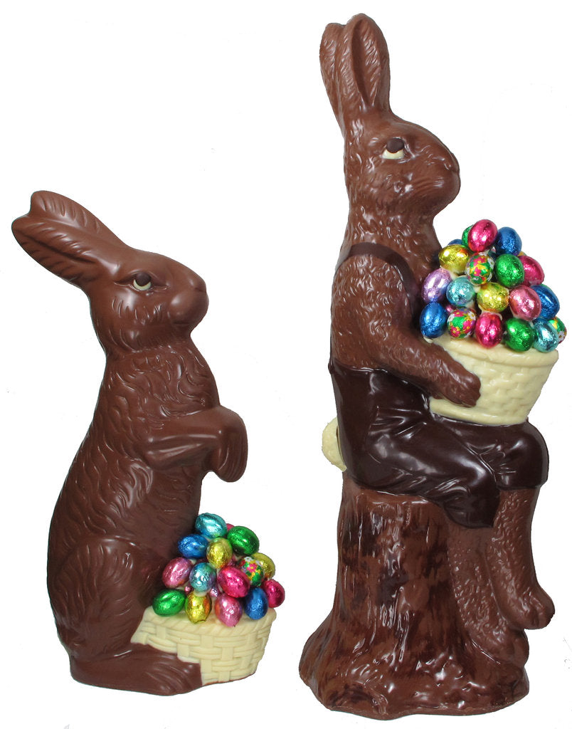 Two chocolate bunnies with Easter eggs; one standing and one sitting on a stump.